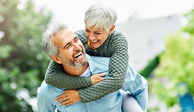 Middle-aged couple smiling after seeing their Cigna dentist in Worthington