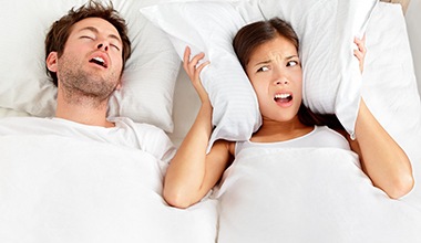 Man snoring in bed next to wife.