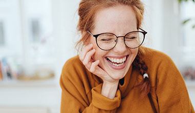 Woman with red hair and white teeth smiling at home