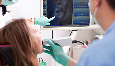 dentist & hygienist using intraoral camera to examine woman's teeth
