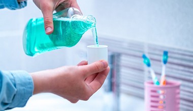 person pouring mouthwash into a cup 