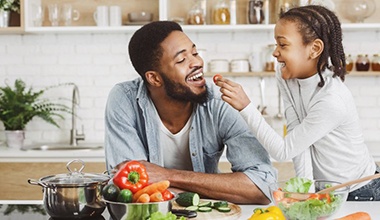 little girl feeding her dad a cherry tomato 