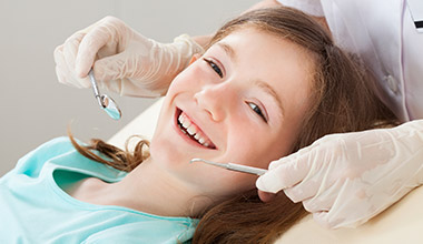 dentist giving smiling girl a dental exam