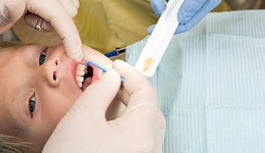 child receiving fluoride treatment from dentist