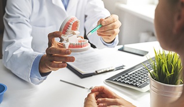 a dentist pointing at a model of teeth