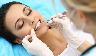 Dentist cleaning woman’s teeth and gums