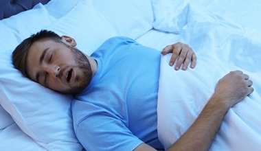 Young man with beard snoring in bed