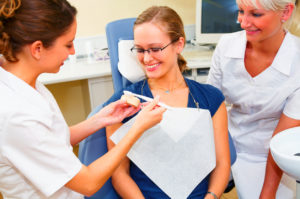 Dentists assisting a female patient with tooth brushing technique