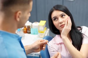 person holding their jaw while talking to dentist