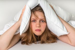person exhausted with a pillow over their head