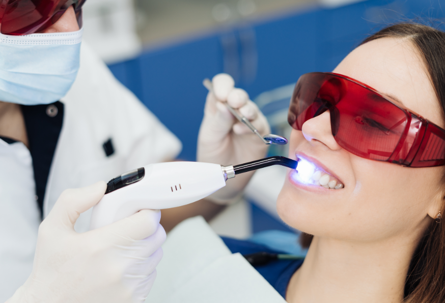Woman getting teeth whitening treatment in dental chair